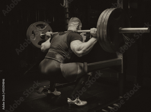 Professional athlete makes squats with a bar photo