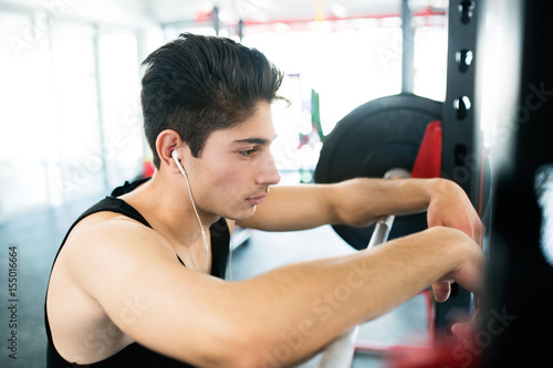Hispanic man in gym resting, earphones in his ears,listening mus