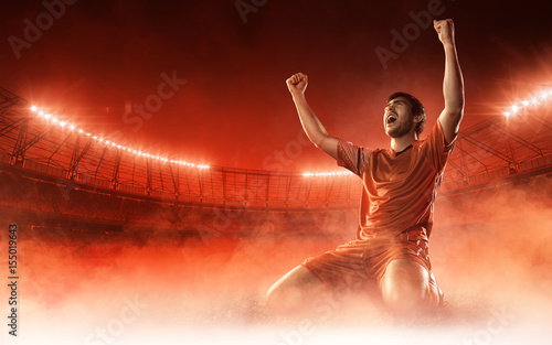 Fotografiet soccer player on soccer stadium celebrating a goal on red smoke background