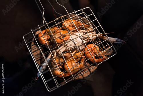 Grilled flower crabs and shrimps on charcoal stove camping at campfire. photo