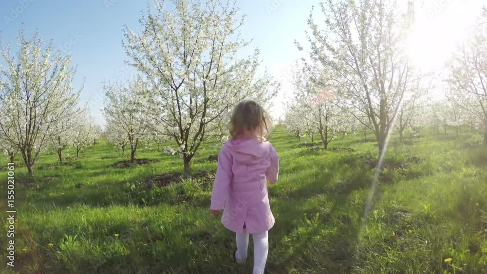 Sweet little curly girl in pink raincoat running away in the garden Sweet little curly girl in pink raincoat running away in the garden
