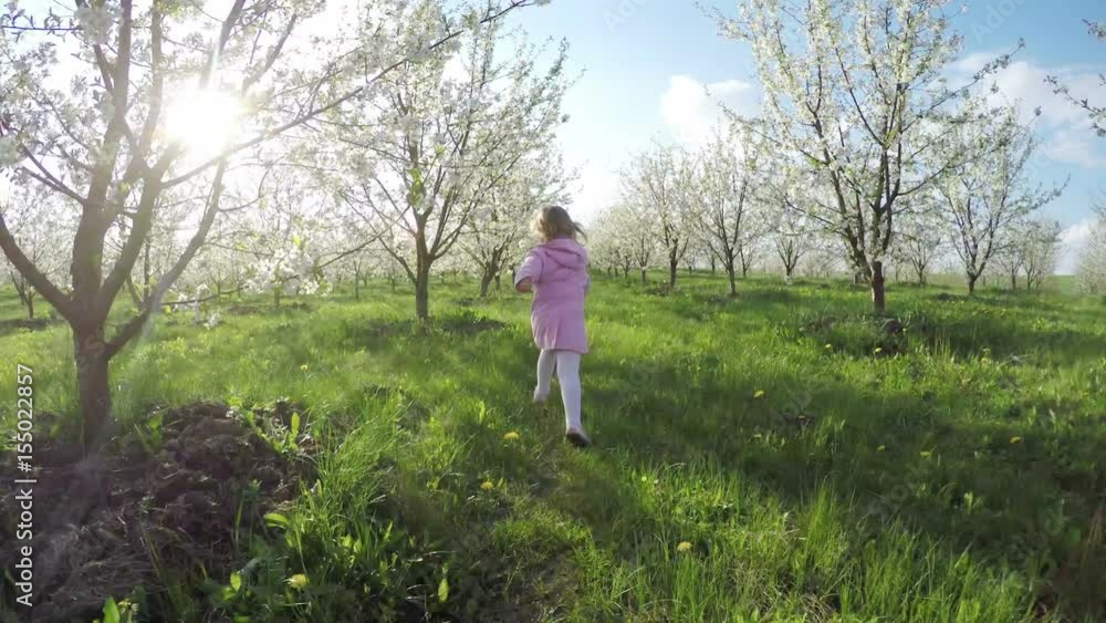 Sweet little curly girl in pink raincoat running away in the garden Sweet little curly girl in pink raincoat running away in the garden