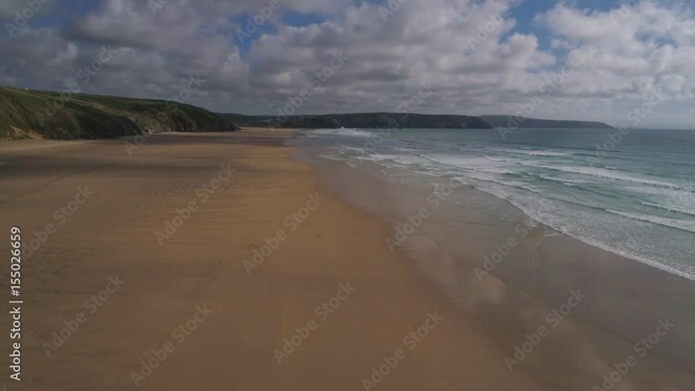 Flying over beautiful sandy beach, aerial seaside landscape with sea and waves, rocky cliffs in the background Flying over beautiful sandy beach, aerial seaside landscape with sea and waves, rocky cliffs in the background