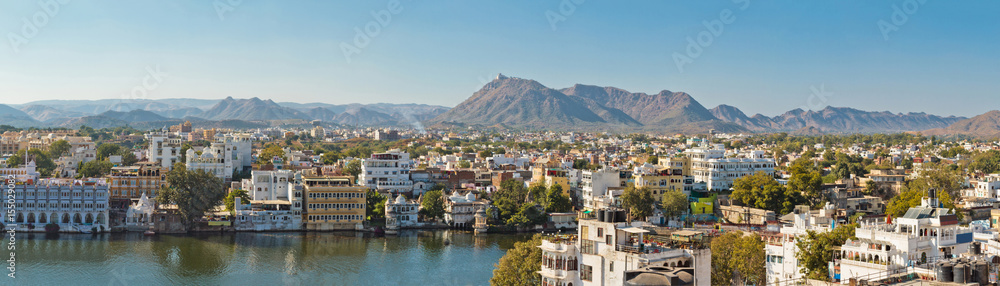 Beautiful panoramic view of Udaipur city in Rajastan, India. Famous Pichola Lake, historical buildings with mountains on background