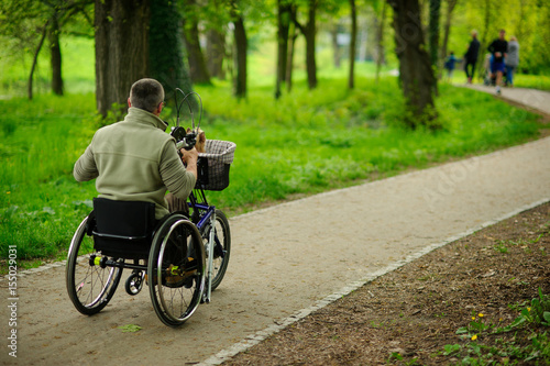 The man in a wheelchair on walk in the spring park.
