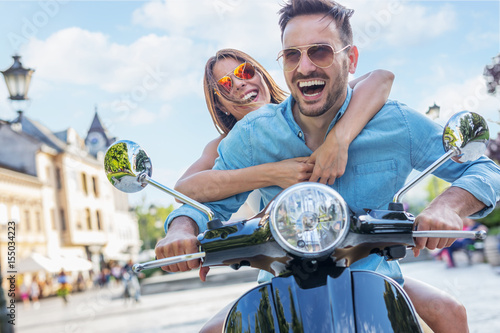 Beautiful young couple riding scooter together.