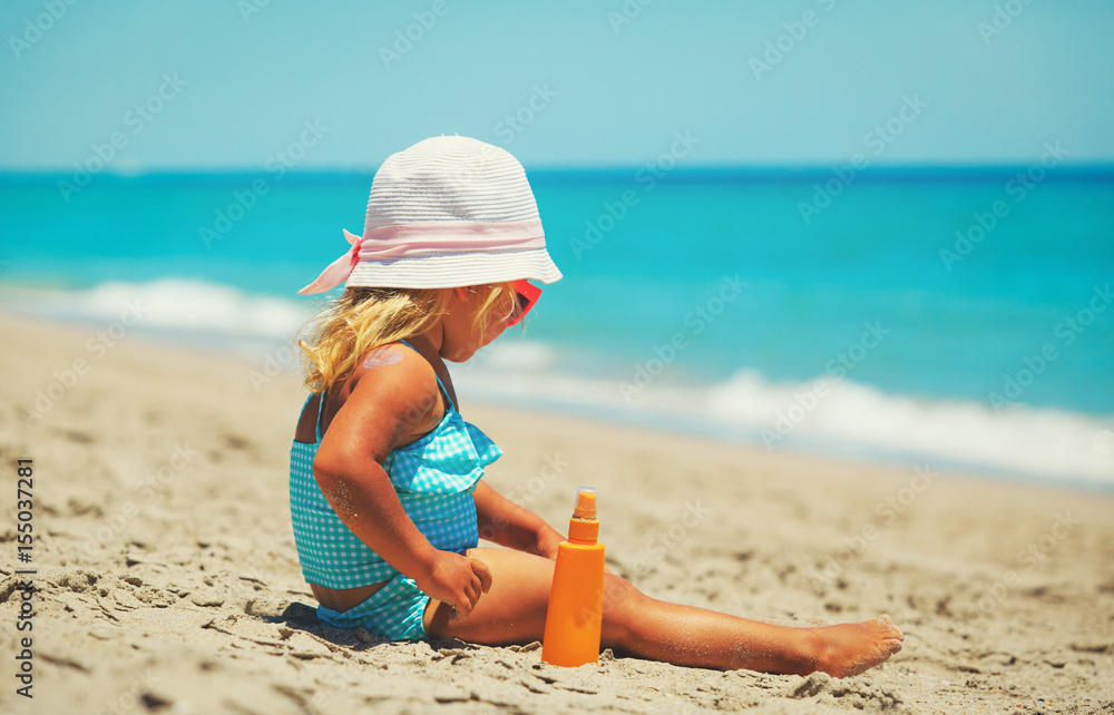 little girl applying sunblock cream on shoulder little girl applying sunblock cream on shoulder