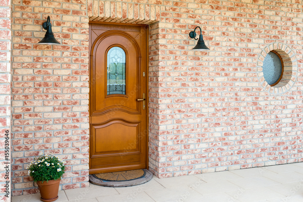 Obraz premium Stylish wooden front - entrance door in a detached house - embedded in a brick wall