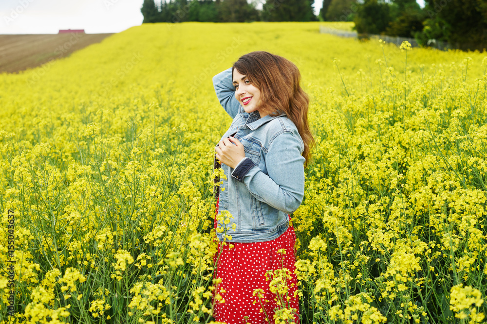 Fototapeta premium A young caucasian woman in rapeseed field