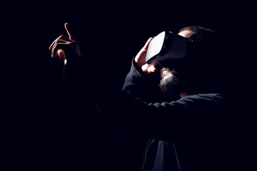 Young hipster bearded man wearing virtual reality goggles. Black background studio VR concept