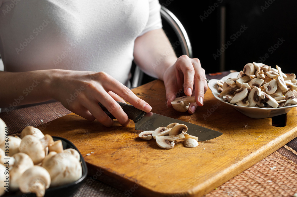 man cutting mushrooms on wooden cutting board