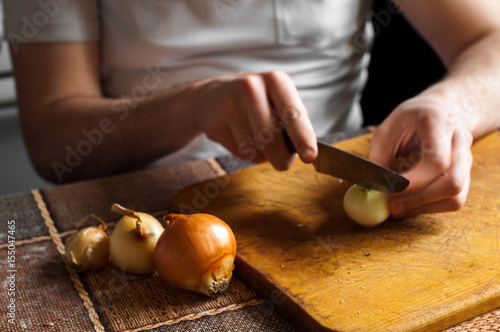 Cutting and chopping an onion on a wooden board with a knife