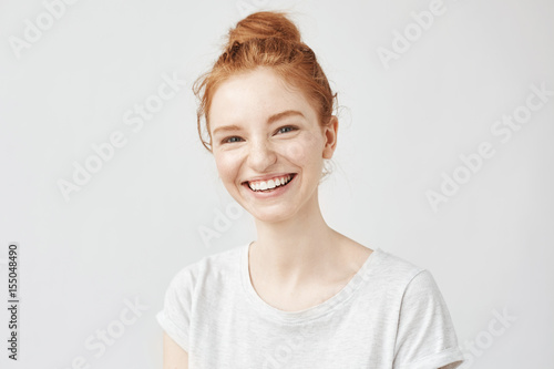 Portrait of cheerful redhead girl with hair bun laughing. photo