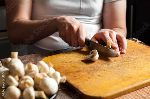 man cutting mushrooms on wooden cutting board