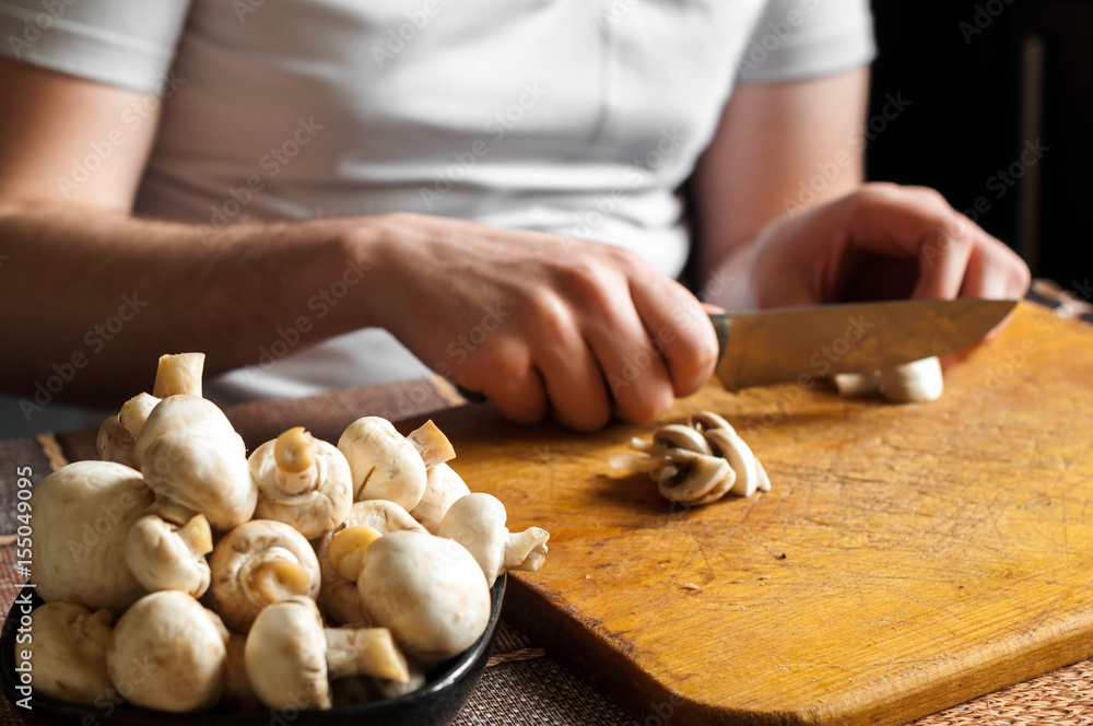 man cutting mushrooms on wooden cutting board man cutting mushrooms on wooden cutting board