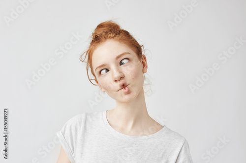 Portrait of funny cute ginger girl with freckles fooling.