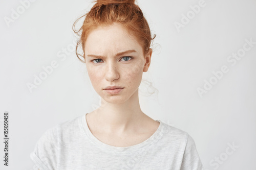 Portrait of beautiful upset redhead girl looking at camera.