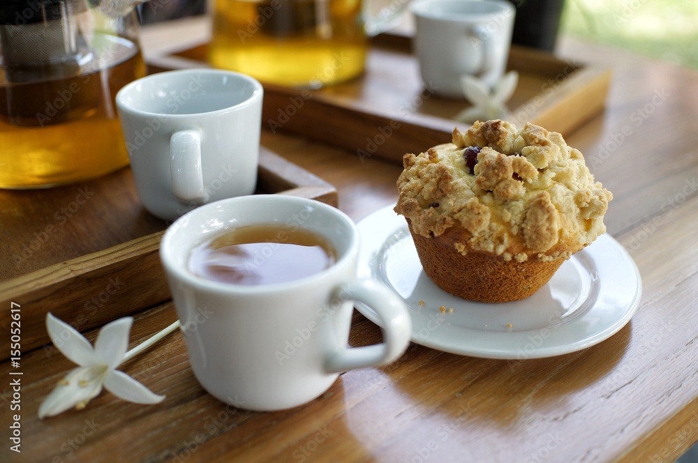 Muffin with a cup of tea on wooden table in the garden Muffin with a cup of tea on wooden table in the garden