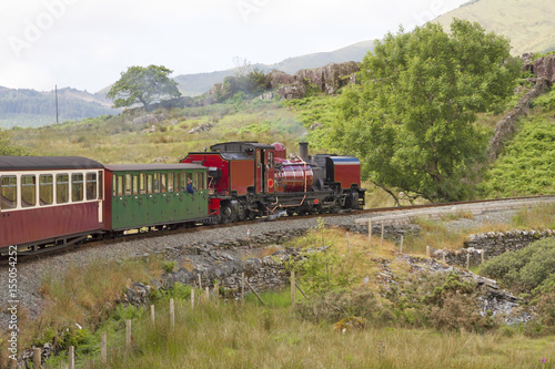 UK - Wales - Red steam locomotive (class garratt) pulls the old heritage train through Wales wilderness on Welsh Highland Railway