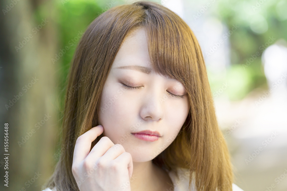 Fototapeta premium 目を閉じて考える若い女性 屋外