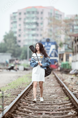 Guitar girl walking on railway tracks. © Wang