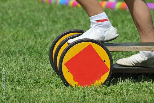 Junge in Turnschläppchen balanciert auf einem Pedalo auf dem Sportplatz