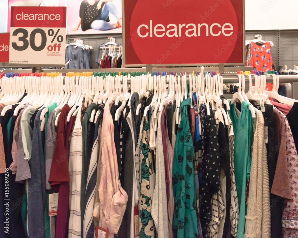 Red clearance sign for 30% off on cloth rack with variety of women apparel  in retail store in America. Stock Photo