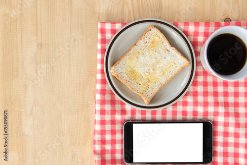 Bread and coffee cup and smart phone on plaid napkin