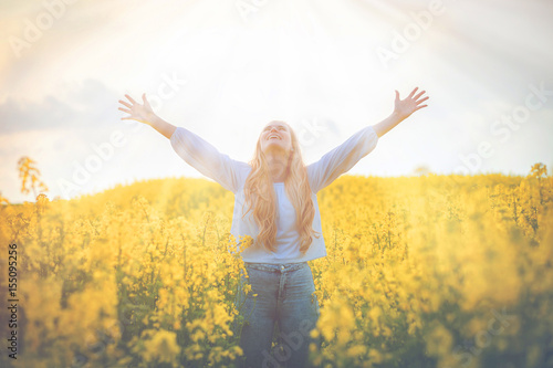 Happy smiling woman in yellow rapeseed field at sunset freedom concept