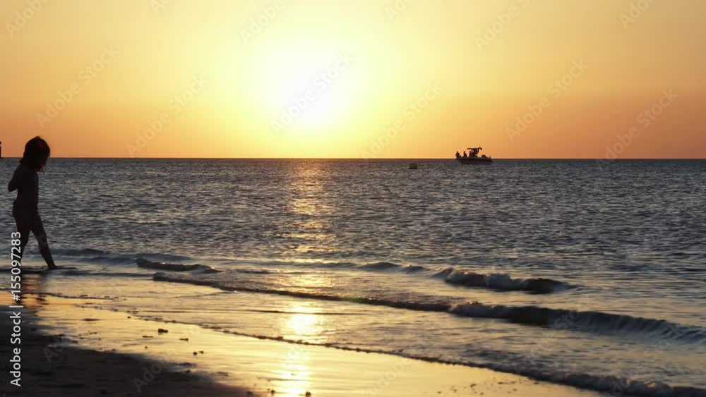 Sunset at the beach. Backlight of a Girl on the shore of the beach at sunset. Sunset at the beach. Backlight of a Girl on the shore of the beach at sunset.