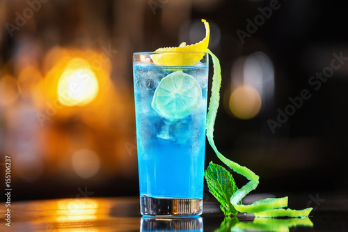 Closeup glass of blue lagoon cocktail decorated with lime at festive bar counter background Fototapet