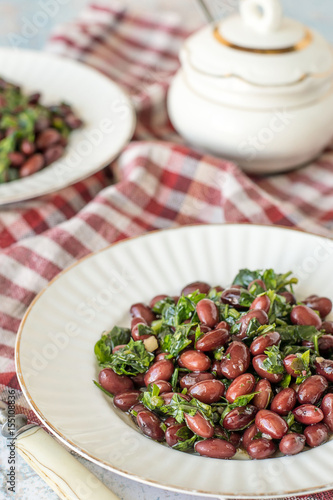 Salad of red beans. Salad of red beans with cilantro and garlic on white plates on a checkered napkin.