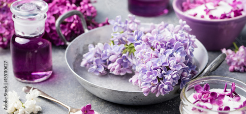 Lilac flowers sugar and syrup  essential oil with flower blossoms in glass jar Grey stone background