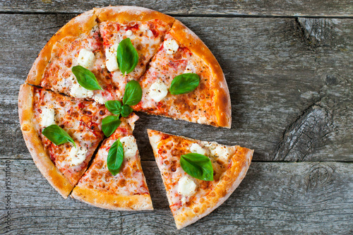 Homemade Pizza with tomato sauce, artichoke hearts, olives, Parmacotto, fresh mozzarella, parmesan and basil on the grey wooden background photo