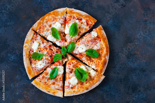 Pizza margarita with tomato sauce, fresh mozzarella, parmesan and basil on the dark background