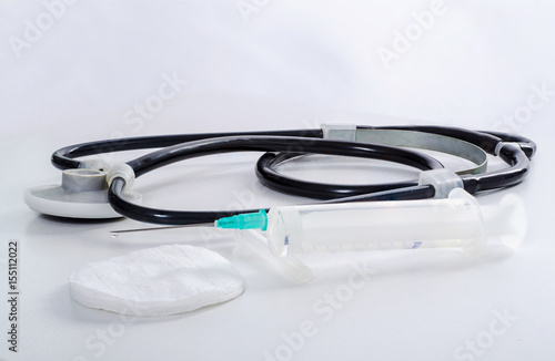 disposable syringe and a black stethoscope on a white background