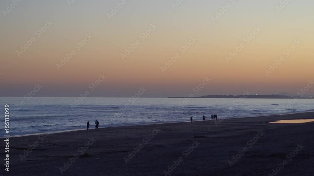 Sunset at the beach. People on the shore of the beach during a beautiful sunset. Sunset at the beach. People on the shore of the beach during a beautiful sunset.