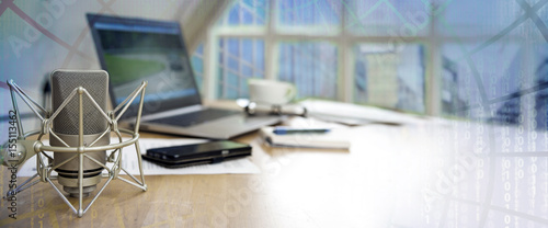 business workspace for international  journalism with microphone, laptop, cell phone and notepad on a desktop, panoramic banner with blurred matrix in the background, copy space photo
