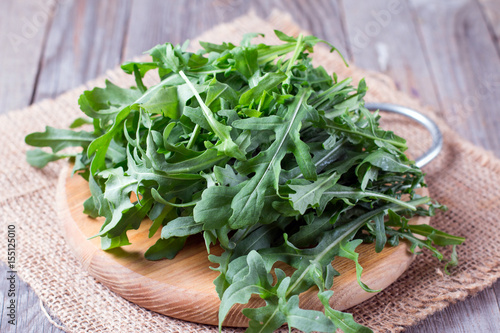 Fresh green arugula in bowl on wooden table