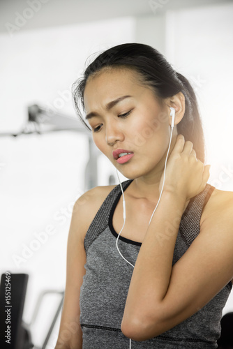 Asian woman in sportswear having neck pain at the gym.