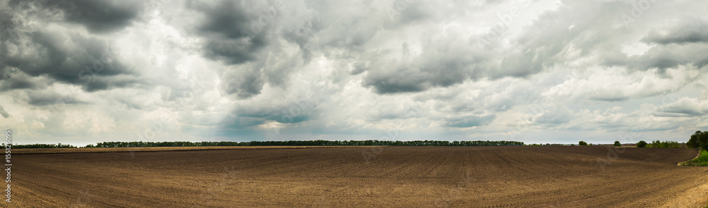 Beautiful Ukrainian landscape with a spring field after planting and dramatic sky.