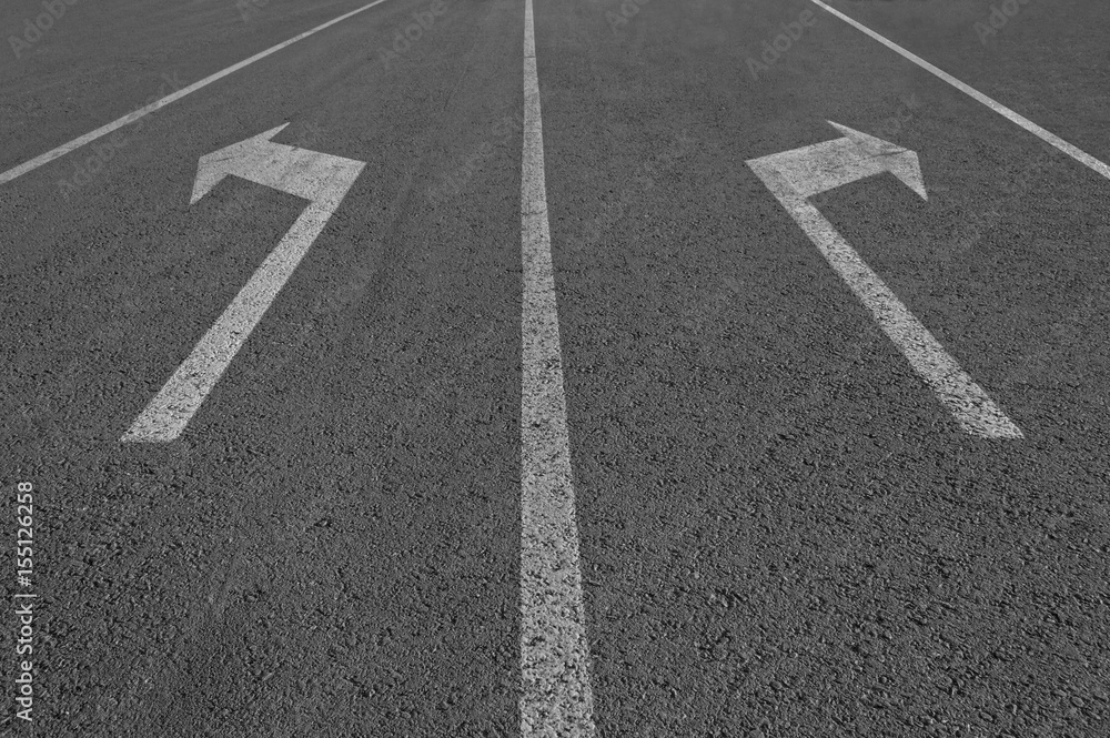 Arrows sign on asphalt road.