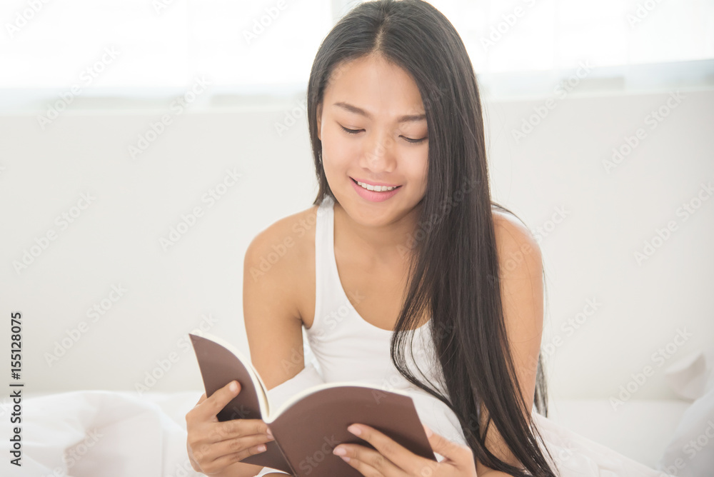 Relaxed Asian girl reading a book on her bed. Relaxed Asian girl reading a book on her bed.