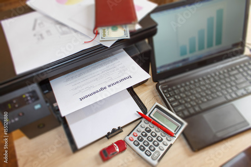 Homeowner and car Insurance form with Laptop, Printer, pen, notebook, calculator on the table photo