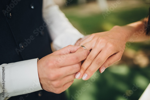 Groom wears a wedding ring on the finger of the bride © AlexGukalovUkraine