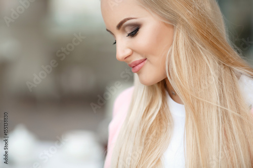 Beautiful autumn woman wear pink jacket posing near the seaa outdoors. Beauty happy long hairl blonde girl smiling at beach. Autumn  style fashion model photo