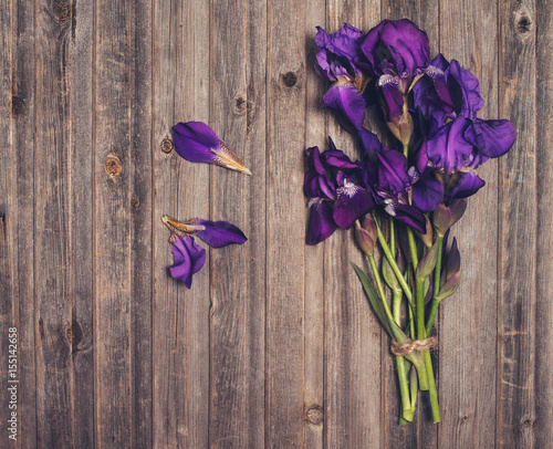 Fototapeta Naklejka Na Ścianę i Meble -  Purple iris flowers bouquet on weathered wooden background. Retro styled floral texture.