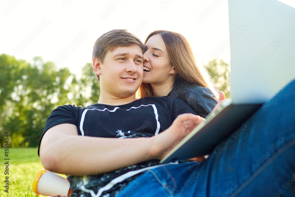 A loving couple with laptop in the park at sunset. A loving couple with laptop in the park at sunset.
