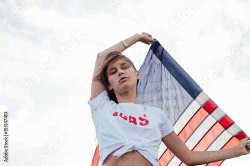 Proud and high minded model looks with suspision and arrogance on the photographer with an american flag in her hands photo