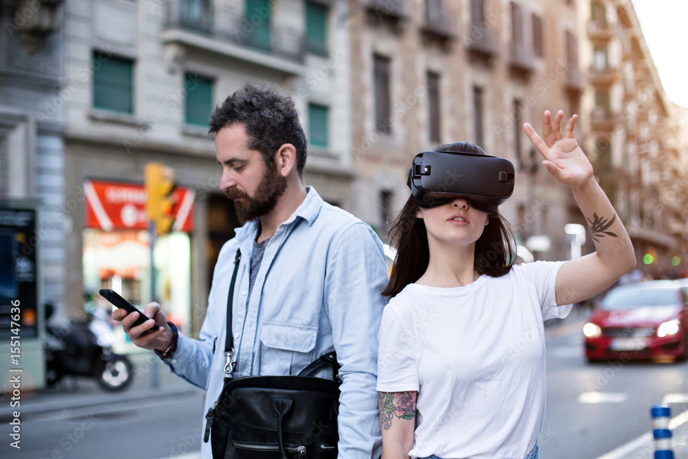 Two tourists explore the new city destination with futuristic technology glasses and smartphone on a busy street in the beautiful sunset Two tourists explore the new city destination with futuristic technology glasses and smartphone on a busy street in the beautiful sunset